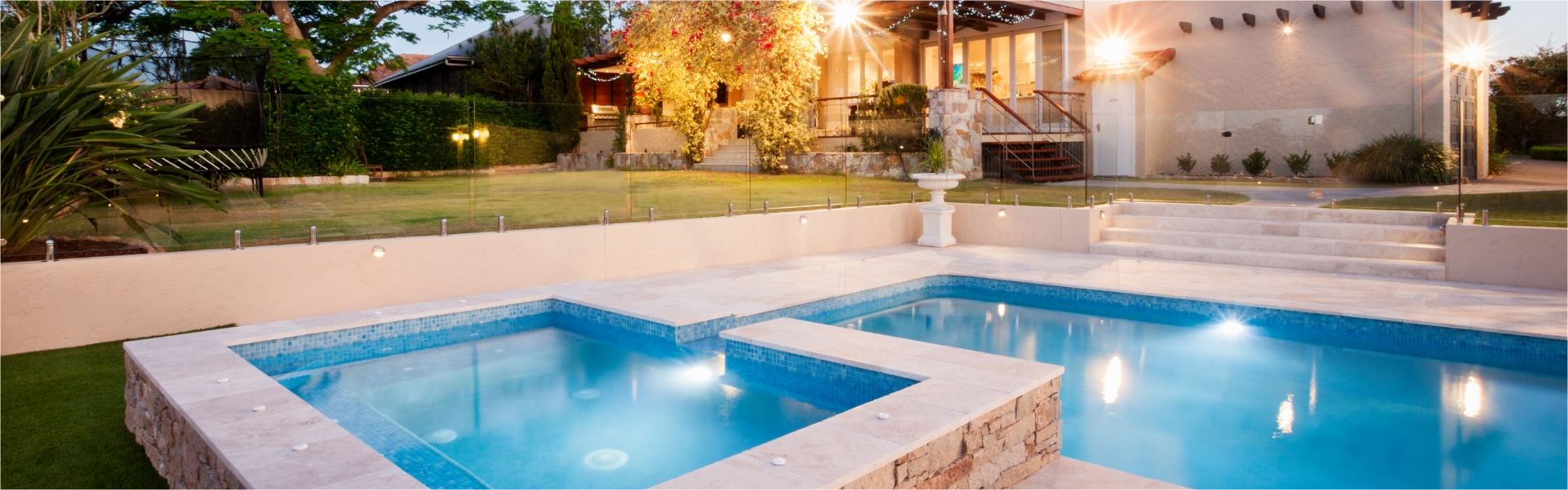 Backyard pool with hot tub at dusk